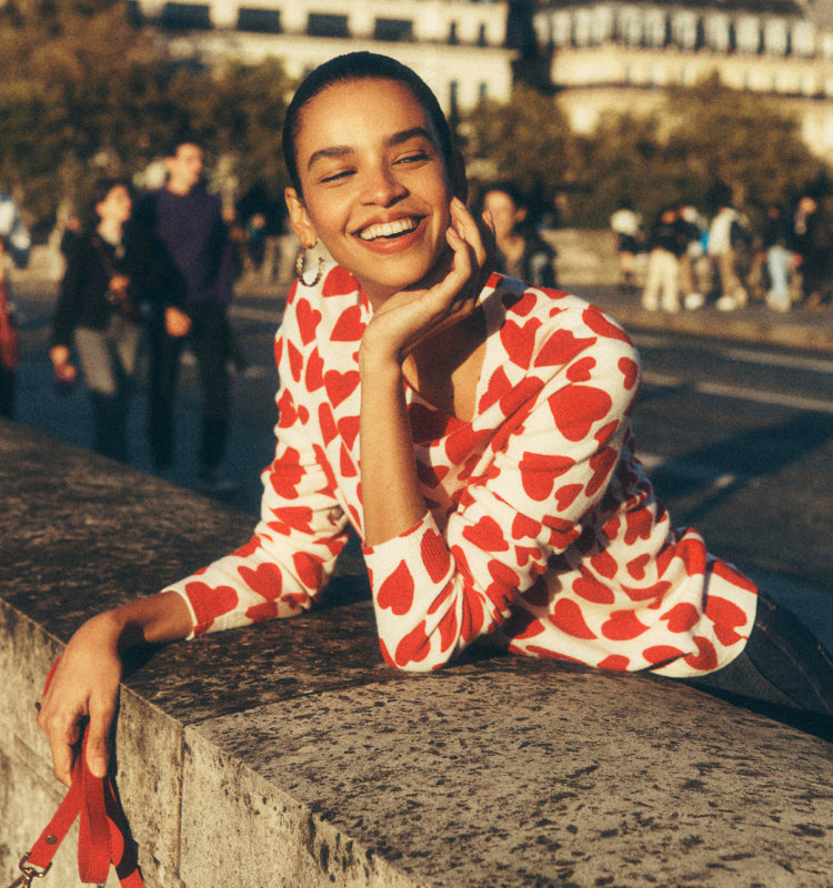 Woman stood on a bridge in Paris wearing a Boden love heart jumper