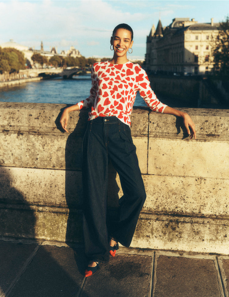 Woman stood on a bridge in Paris wearing a Boden love heart jumper