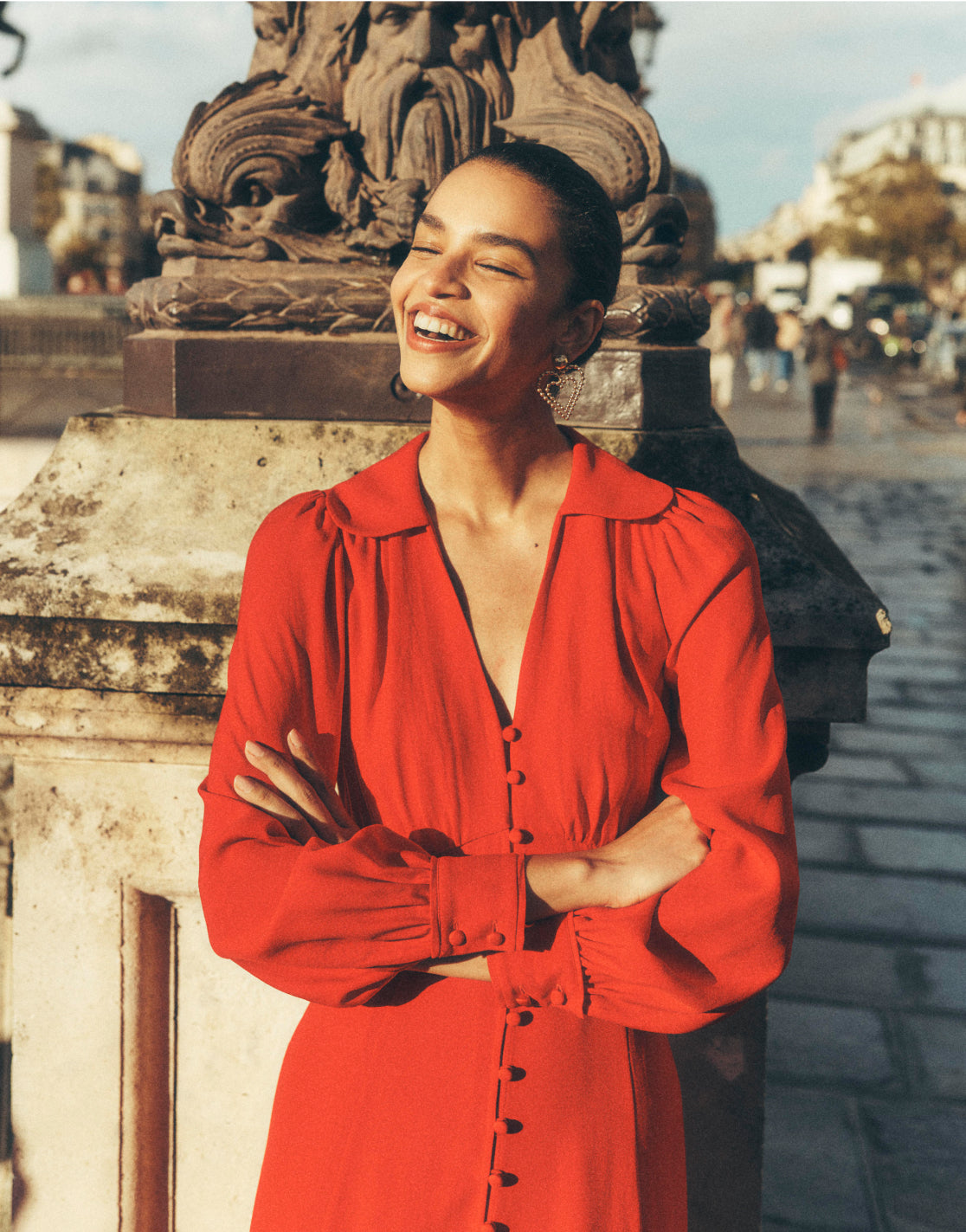 Woman stood on a bridge in Paris wearing a red Boden dress