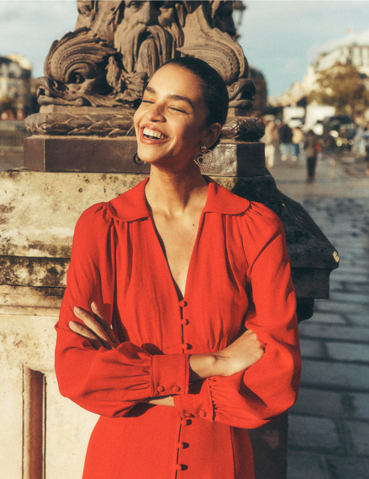 Woman stood on a bridge in Paris wearing a red Boden dress