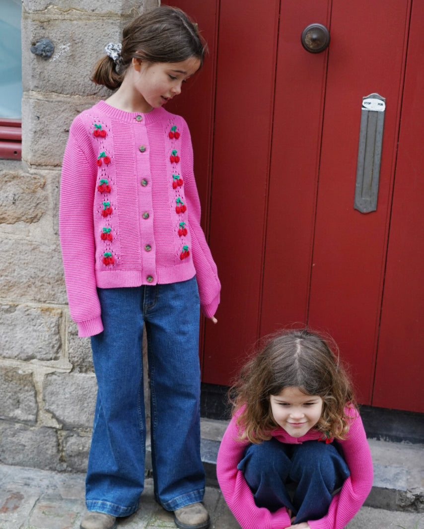 Two girts wearing pink matching knitwear 