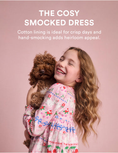 Annotated picture of a girl holding a dog, wearing a pink smocked Boden dress