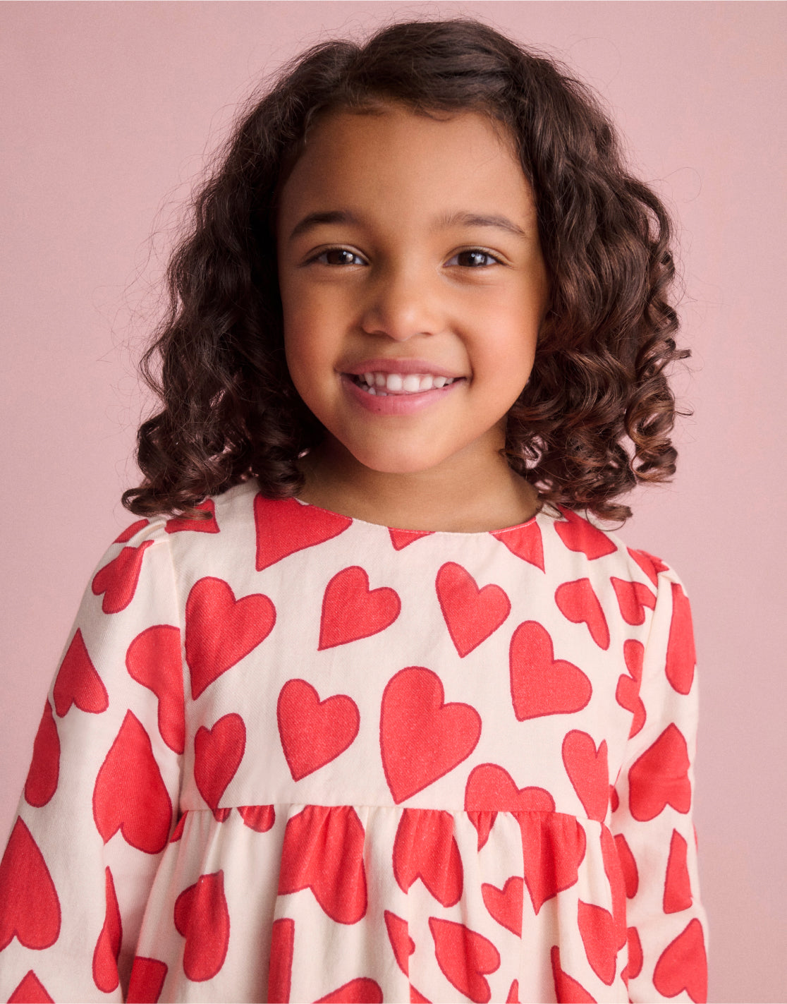 girl smiling wearing heart printed dress