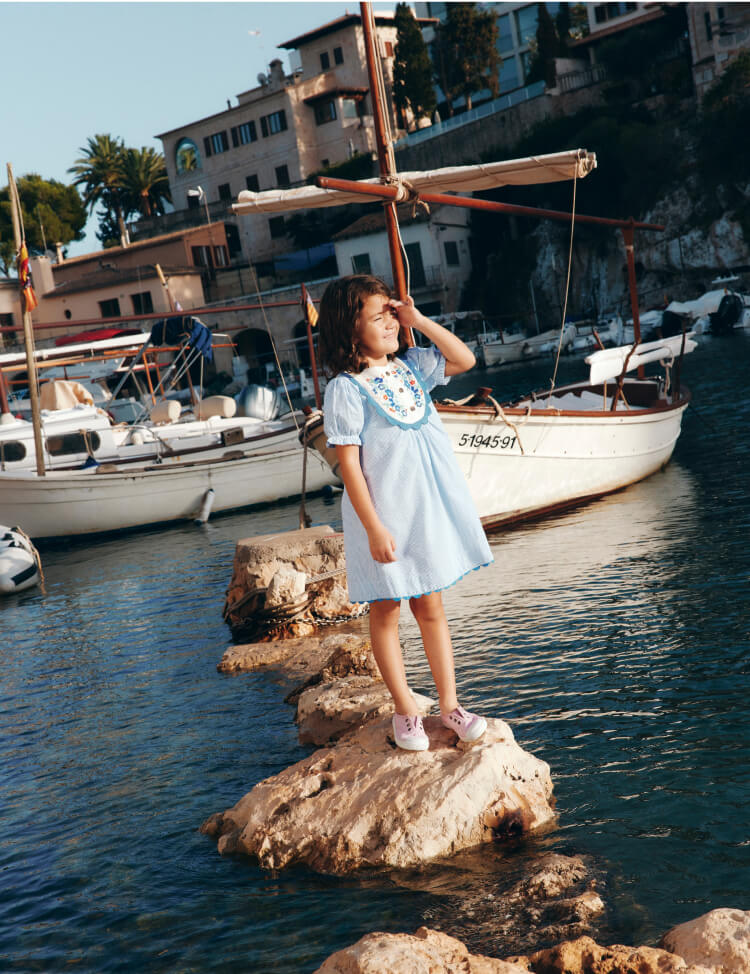 girl standing on rock in blue dress